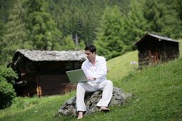 Mann mittleren Alters arbeitet an einem Laptop, Heiligenblut, Hohe Tauern Nationalpark, Kärnten, Österreich