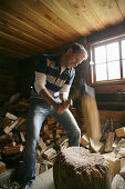 Mann beim Holzhacken auf einer Alm, Heiligenblut, Nationalpark Hohe Tauern, Kärnten, Österreich