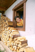Woman looking out of a window and waving, Heiligenblut, Hohe Tauern National Park, Carinthia, Austria
