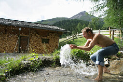Mann erfrischt sich an einem Gebirgsbach, Heiligenblut, Nationalpark Hohe Tauern, Kärnten, Österreich