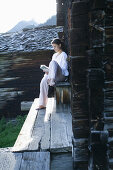 Woman reading a book in front of alp lodge, Heiligenblut, Hohe Tauern National Park, Carinthia, Austria