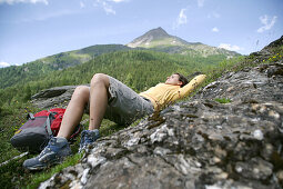 Woman lying on grass, mountains in background, Heiligenblut, Hohe Tauern National Park, Carinthia, Austria