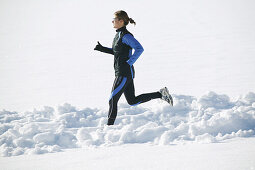 Woman jogging on snowy road, Styria, Austria