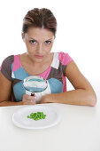 Woman observing peas on a plate through magnifying glass, Styria, Austria