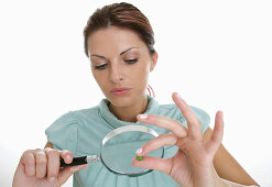 Woman observing pea with magnifying glass, Styria, Austria