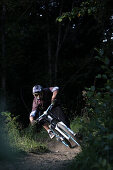 Mountain biker riding over forest track, Oberammergau, Bavaria, Germany