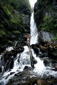 Naked young man standing in front of a waterfall, See, Tyrol, Austria