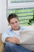 Junger Mann liest Zeitung, München, Deutschland