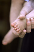 Hand holding baby foot.