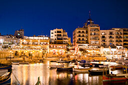 Boats at a bay in front of illuminated houses, Spinola Bay, St. Julian´s, Malta, Europe