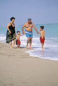 Mature couple with grandchildren walking at the beach, Florida, USA