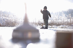 Junge spielt Eisstockschießen auf dem Buchsee, Münsing, Bayern, Deutschland