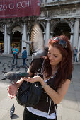 Frau füttert Tauben am Markusplatz, Venedig, Venetien, Italien, Europa