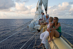Passagiere entspannen sich auf dem Bugspriet vom Großsegler Star Flyer, Rangiroa, Tuamotu Inseln, Französisch Polynesien, Südsee