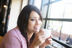 21 year old girl, sitting in bar drinking coffee smiling