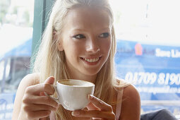 21 year old girl sitting in a cafe drinking coffee
