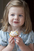 Little girl s third birthday party, eating a bun, smiling