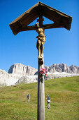 Wooden cross, two hikers in background, Dolomite Alps, South Tyrol, Italy