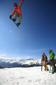 Snowboarder jumping in front of friends, See, Tyrol, Austria