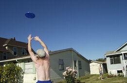  Activity, Adult, Adults, Back view, Backyard, Backyards, Carefree, Color, Colour, Contemporary, Daytime, Disk, Disks, Exterior, Frisbee, Frisbees, Holiday, Holidays, Horizontal, House, Houses, Housing, Human, Leisure, Lifestyle, Lifestyles, Male, Man, Me