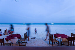 People passing a beach restaurant, The Sands, at Nomad, Diani Beach, Kenya