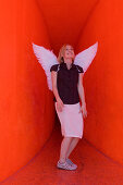 Mid adult woman wearing angel wings in a red tunnel