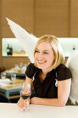 Engel, junge Frau mit Engelsflügeln trinkt ein Glass Rotwein, Restaurant, München, Bayern, Deutschland