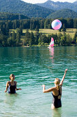 Two young women playing with a ball in lake Walchensee, Bavaria, Germany