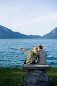 Two young women sitting a lakeshore of lake Walchensee, Bavaria, Germany