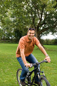 Mid adult man cycling over meadow