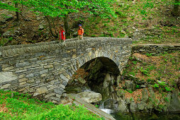 young couple crossing stone bridge, Ticino, Switzerland