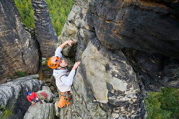 A young man rock climbing at the small Hercules Column, Alter Weg in Bielatal, Elbe Sandstone Mountains, Saxon Switzerland, Saxony, Germany