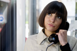 Junge Frau telefoniert in einer Telefonzelle, Düsseldorf, Nordrhein-Westfalen, Deutschland