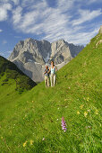 Couple hiking over meadow, Karwendel range, Tyrol, Austria