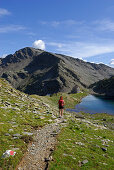 young woman on the way to hut Flaggerschartenhütte with lake, Marburg-Siegener Hütte, Rifugio Forcella di Vallaga, Sarntal range, South Tyrol, Alta Badia, Italy