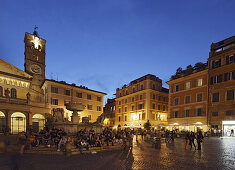 Personen sitzen auf den Stufen von einem Brunnen, Kirche Santa Maria in Trastevere im Hintergrund, Rom, Italien