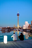 Menschenauf einer Brücke vor Rheinturm, Frank O. Gehry Bauten, Medienhafen, Düsseldorf, Nordrhein-Westfalen, Deutschland, Europa