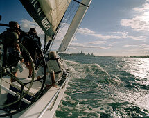 Three men on a sailing boat at full speed, Waitemata Harbour on the horizon, Auckland, North Island, New Zealand