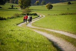Four people running along dirt road, Munsing, Bavaria, Germany