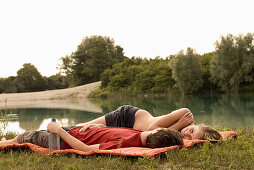 Young couple lying on blanket at lakeshore, Freising, Bavaria, Germany