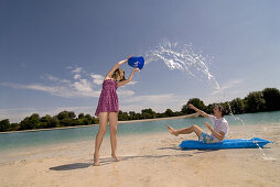 Teenage girl dashing boyfriend with water, Freising, Bavaria, Germany