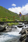 Woman on a bridge crossing stream, Texel range, Oetztal range, South Tyrol, Italy
