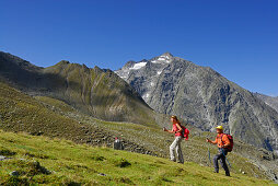 couple on trail through green meadow, Lisenser Fernerkogel in background, Luesener Fernerkogel, Sellrain range, Stubaier Alpen range, Stubai, Tyrol, Austria