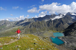 young woman hiking, ascent to Rinnenspitze, view to lake Rinnensee and Ruderhofspitze, Stubaier Alpen range, Stubai, Tyrol, Austria