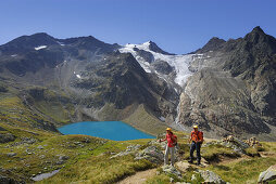 Couple hiking above lake Gruenau, Stubai Alps, Stubai, Tyrol, Austria