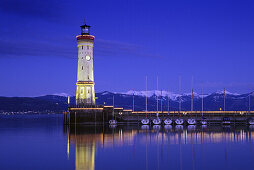 Leuchtturm an der Hafenausfahrt am Abend, verschneite Alpen im Hintergrund, Lindau, Bodensee, Baden-Württemberg, Deutschland