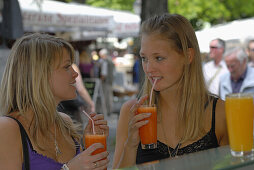 Two young women drinking freshly juice, Viktualienmarkt, Munich, Bavaria, Germany