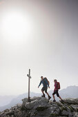 Hikers arriving summit cross, Werdenfelser Land, Bavaria, Germany