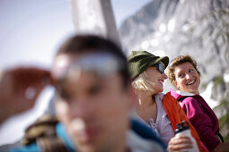 Hikers resting at summit cross, Werdenfelser Land, Bavaria, Germany