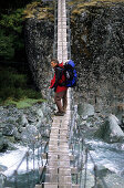 Mann auf einer Hängebrücke über dem Rees Dart River, Mt. Aspiring Nationalpark, Südinsel, Neuseeland, Ozeanien